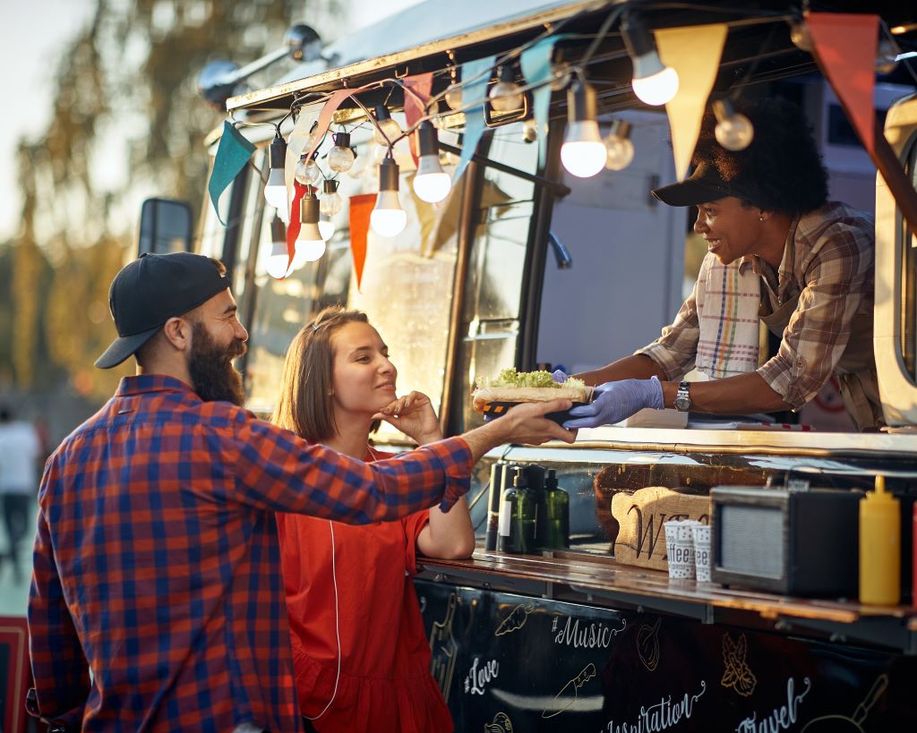 couple buying plate from lady in food truck